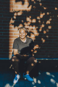 Portrait of smiling young man sitting against wall