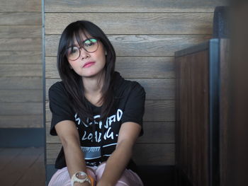 Portrait of woman sitting against wall