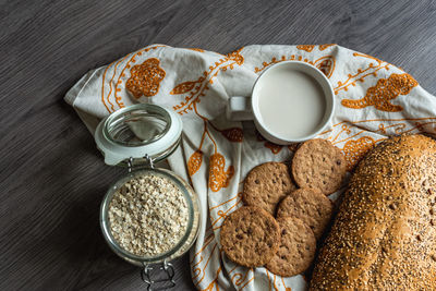 Top view of breakfast with bread, milk, cookies and oatmeal.