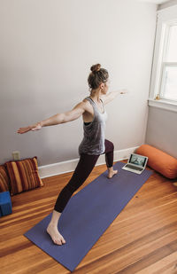 Woman with arms raised on floor at home