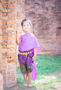 Portrait of smiling girl standing against wall
