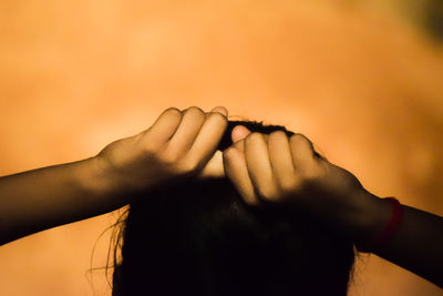 Close-up of woman hand against orange sky