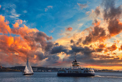 Sailboats sailing in sea against sky during sunset