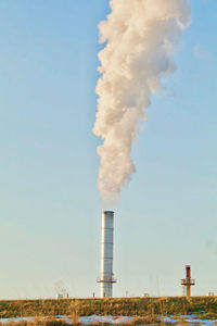 Smoke emitting from chimney against sky