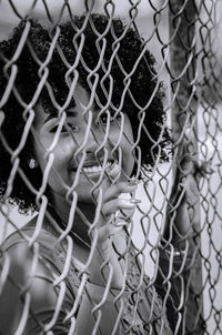 Portrait of woman seen through chainlink fence