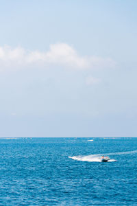 Boat splashing water in sea against sky