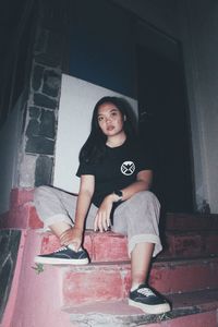 Portrait of a young woman sitting on wall