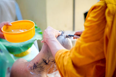 Close-up of person shaving man head with razor