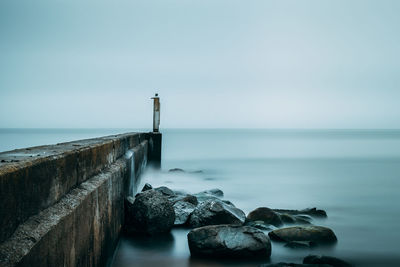 Lighthouse by sea against clear sky