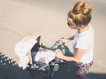 High angle view of woman with baby stroller walking on road