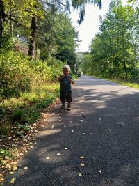 Boy standing on footpath by road