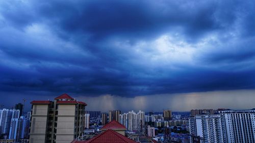 Buildings in city against dramatic sky