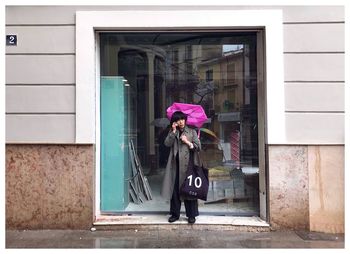 Woman standing on footpath against building