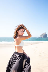 Young woman wearing sunglasses on beach against sky