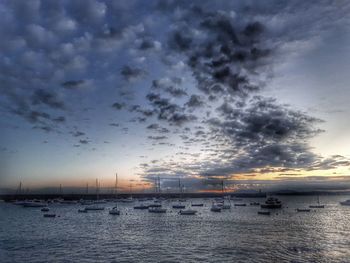 Sailboats moored in sea at sunset