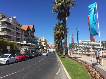 Cars on road by buildings in city against clear sky