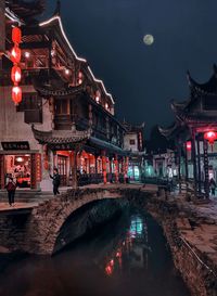 Illuminated bridge over canal in city at night