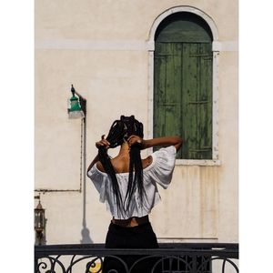 Rear view of woman adjusting hair against building