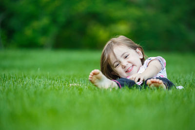 Portrait of young woman lying on grassy field