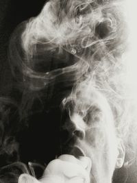 Close-up of man smoking against black background