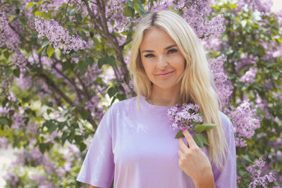 Portrait of young woman standing against trees