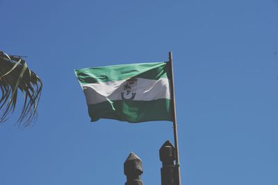 Low angle view of flags against clear blue sky