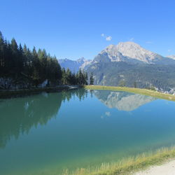 Scenic view of lake and mountains against blue sky