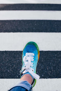 Low section of person wearing multi colored shoes walking on road