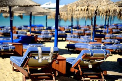 Deck chairs by parasols at beach on sunny day