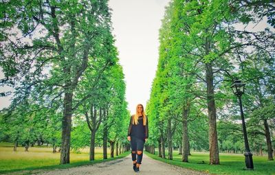 Woman standing on footpath amidst tree