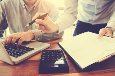 Midsection of man using mobile phone while sitting on table