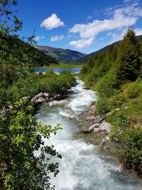 Scenic view of river against cloudy sky