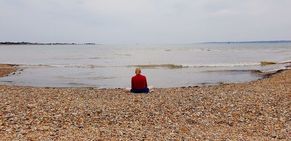 Rear view of woman on beach against sky