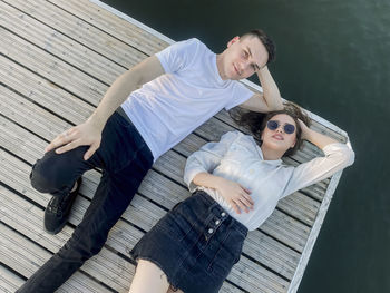 Directly above shot of couple lying on pier over lake