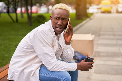 Young man talking on phone while sitting at park