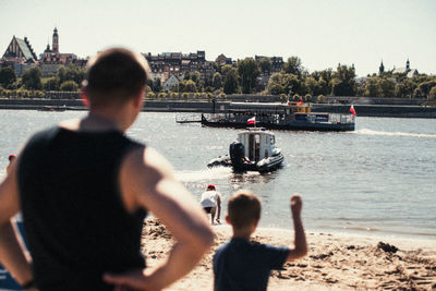 Rear view of people standing in river