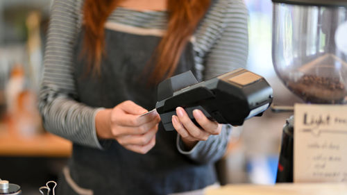 Cropped shot, female barista taking credit card out of payment terminal