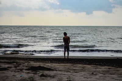 Rear view of man looking at sea against sky