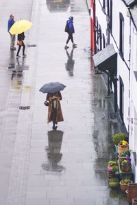 High angle view of people walking on footpath during rainy season