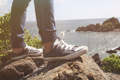 Low section of person on rock by sea