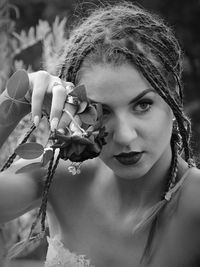 Close-up of young woman with rose looking away outdoors