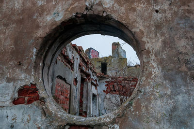 Abandoned building seen through hole in wall