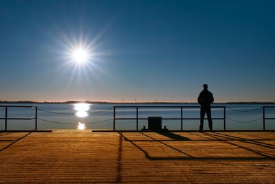 Man stand on wharf construction and looking at sea. sunny clear blue sky, smooth water level