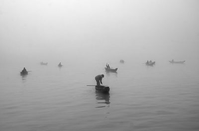 Man in boat on river against sky during foggy weather