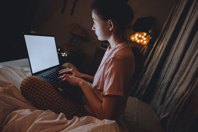 Man using mobile phone while sitting on bed at home