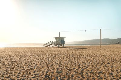 Lifeguard hut on empty beach against clear sky