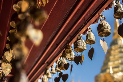 Low angle view of light bulbs hanging from ceiling of building