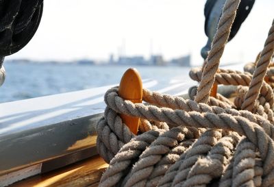 Close-up of rope tied on bollard by sea against sky