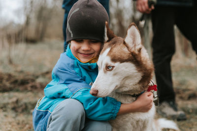 Kid and his friend husky siberian dog. portrait little child boy hugging cute white brown animal pet