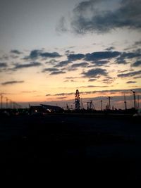 Silhouette cranes against sky during sunset